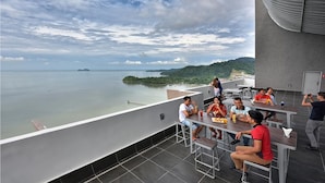 Une terrasse sur le toit offrant une vue sur la mer et les îles, avec des espaces de détente en plein air et un design moderne.