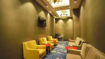 A conference room with yellow chairs, beige sofas, and red tables.