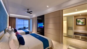 Une chambre d’hôtel avec deux lits, un ventilateur de plafond, une télévision et une vue sur l’océan.