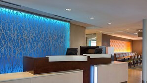 A hotel reception area with a modern design, featuring a reception desk, seating area, and a decorative wall with a blue pattern. - Fairfield Inn & Suites Dallas West/i-30 (Dallas)