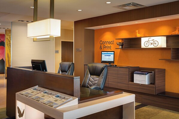 A reception area with a desk, chairs, a computer, and a sign that reads "Connect & Print".