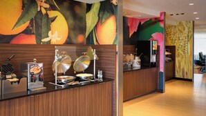 A breakfast bar with waffle makers, a coffee machine, and a fruit-themed mural. - Fairfield Inn & Suites Dallas West/i-30 (Dallas)