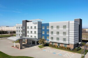 A multi-story hotel with a flat roof, a covered entrance, and a parking lot with handicapped spaces.