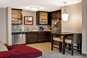 Una cocina compacta con armarios de madera oscura, electrodomésticos de acero inoxidable y encimera de mármol.