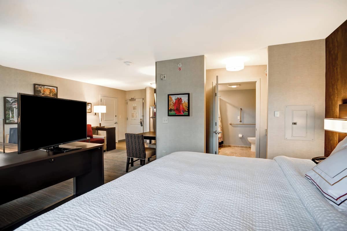 Une chambre d’hôtel comprenant un lit, un bureau avec un téléviseur à écran plat, une chaise, une salle de bain et un escalier.