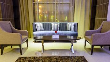 Un vestíbulo moderno con un sofá, dos sillones, una mesa de centro y una alfombra estampada.
