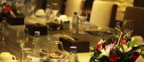 A dining table set with wine glasses, water bottles, and a centerpiece of flowers.