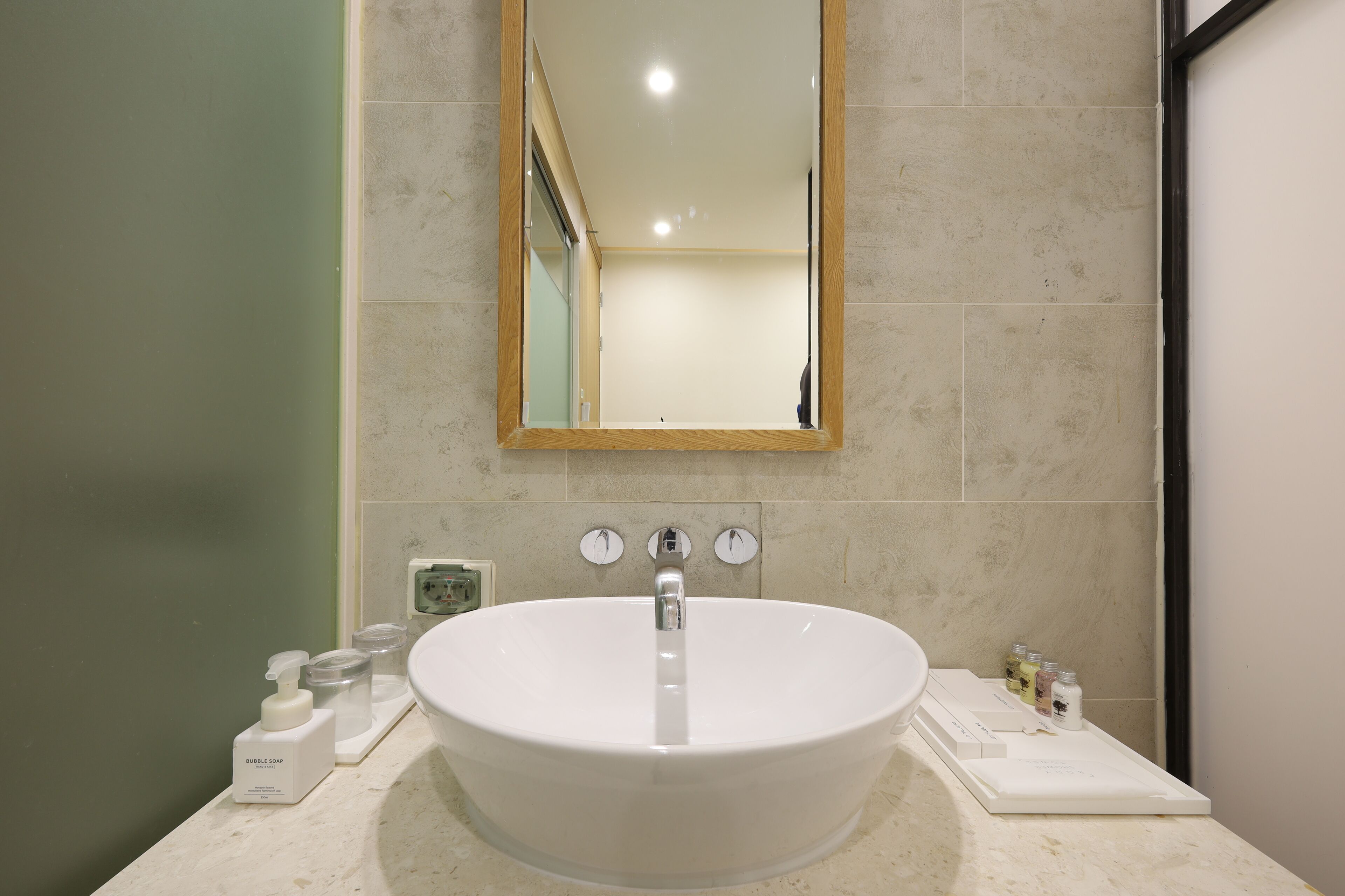 Une salle de bain avec un lavabo blanc, un miroir et des articles de toilette posés sur le comptoir.