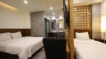 Habitación de hotel con dos camas, un escritorio, una silla, un espejo y un separador de madera.
