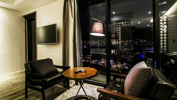 Una sala de estar moderna con un sofá, una mesita redonda y un televisor montado en la pared.