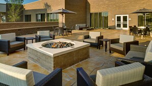 Un patio al aire libre con mobiliario de mimbre, una chimenea y sombrillas.