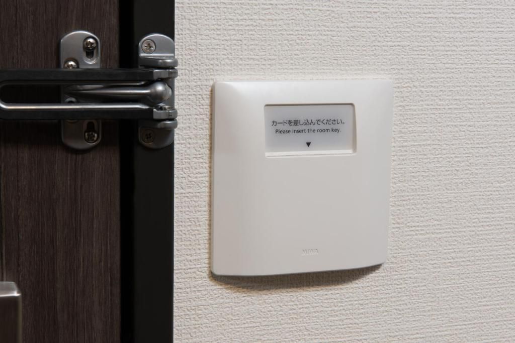Une porte dotée d’une serrure et d’un lecteur de carte fixé au mur, avec des instructions en japonais.