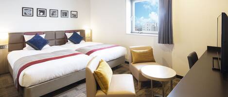 Een hotelkamer met twee bedden, een bank, een klein tafeltje en een televisie.