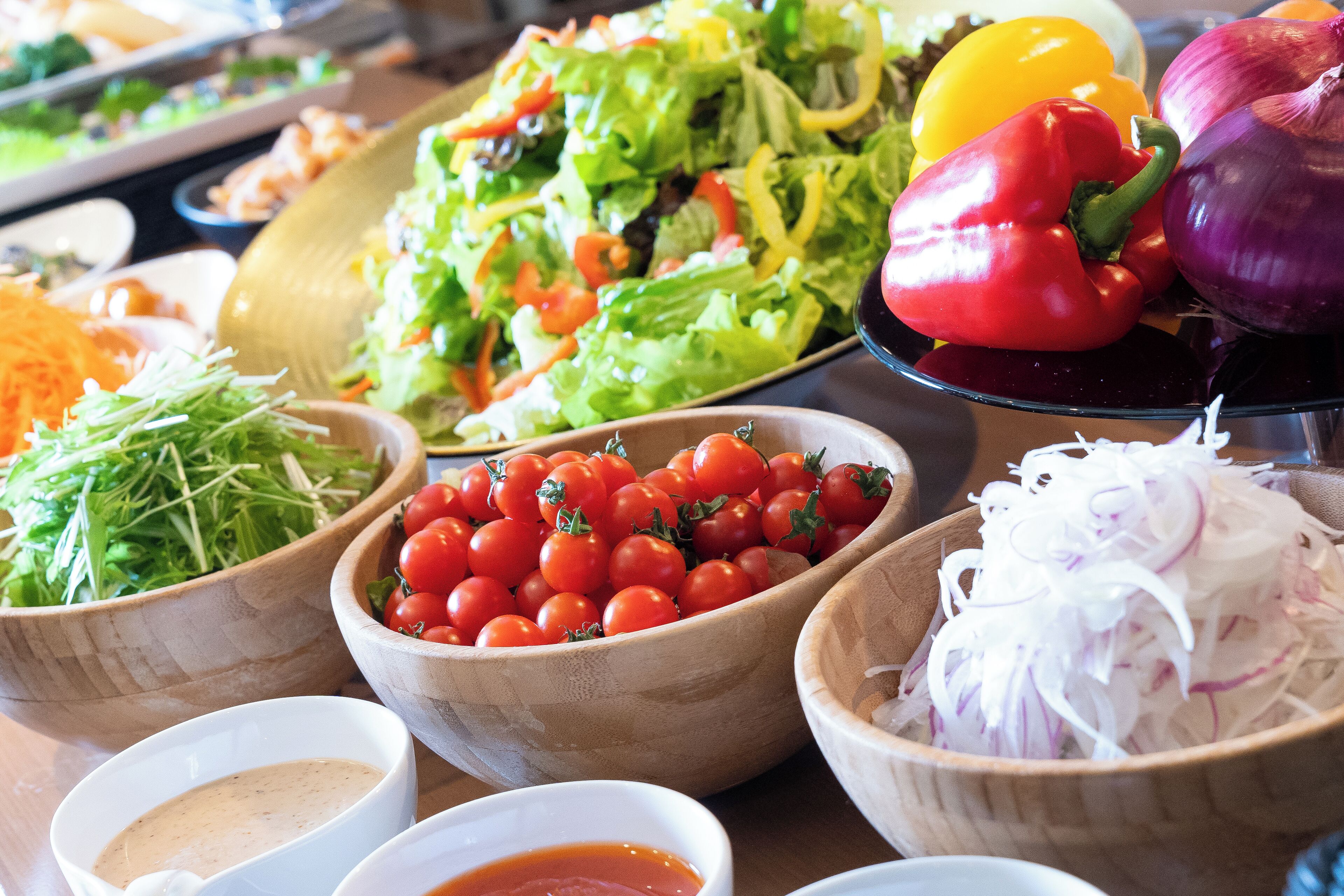 A variety of fresh vegetables and salads displayed in wooden bowls.