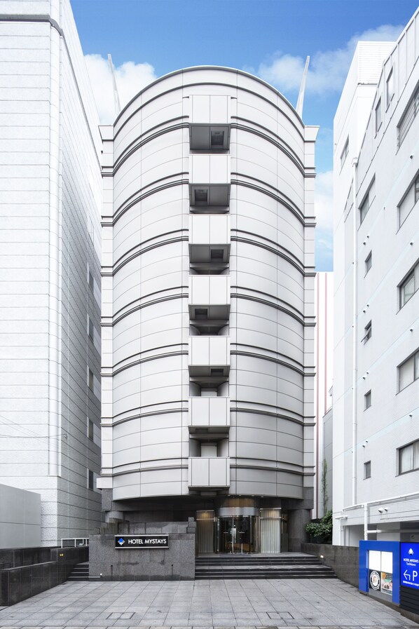 Un hotel moderno con fachada curva, varios balcones y un cartel que indica que es Hotel Mystays.