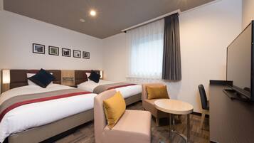 Een hotelkamer met twee bedden, een kleine bank, een ronde tafel en een bureau.