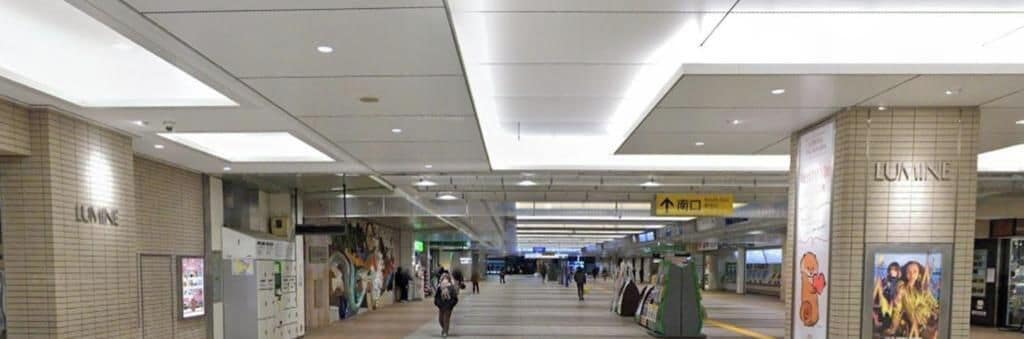 Een ruime binnenhal met verlichting, richtingaanwijzers en advertenties op de muren.