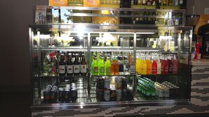 Uma área de bar com prateleiras repletas de diversas bebidas alcoólicas e latas.