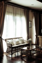 Una habitación con un sofá de mimbre, una mesa de centro de cristal y una silla de mimbre.