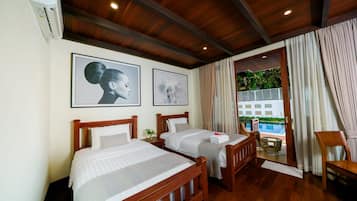 Habitación de hotel con dos camas, cabeceros de madera, un ventanal con cortinas y vista a una piscina.
