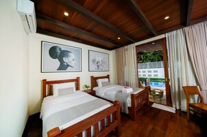 Habitación de hotel con dos camas, cabeceros de madera, un ventanal con cortinas y vista a una piscina.