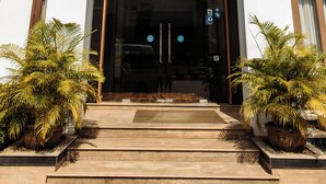 A hotel entrance with a double door, a balcony, and potted plants. - Athena Hotel (Pakse)