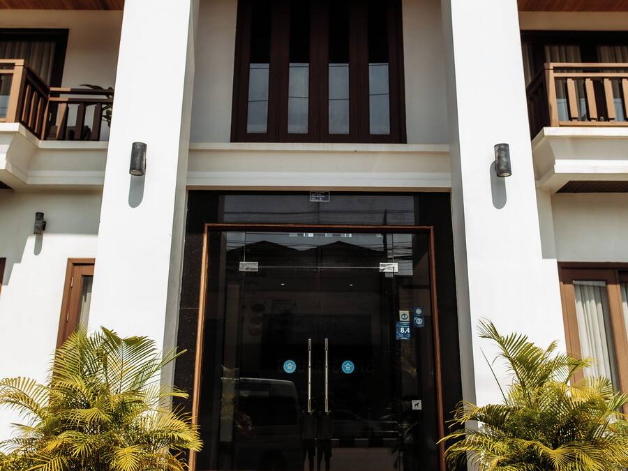 A hotel entrance with a double door, a balcony, and potted plants.