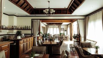 A spacious dining area with high ceilings, wooden beams, and a central chandelier.