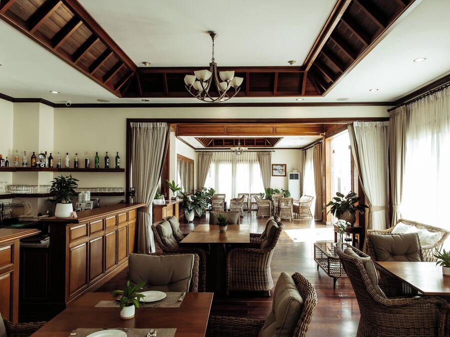 A spacious dining area with high ceilings, wooden beams, and a central chandelier.