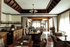 Un comedor amplio con techos altos, vigas de madera y una lámpara central.