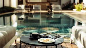 A poolside setting with a table, a cup, and a plate with food. - Athena Hotel (Pakse)