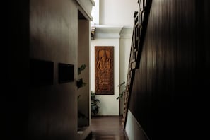 A narrow hallway with a wooden door at the end, a wooden panel wall, and a potted plant. - Athena Hotel (Pakse)