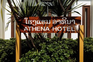 Un letrero de madera con escritura tailandesa y 'ATHENA HOTEL' en inglés, que indica el nombre del hotel.
