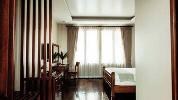 Un dormitorio con una cama de madera, un escritorio con una silla, un espejo y una planta en maceta.