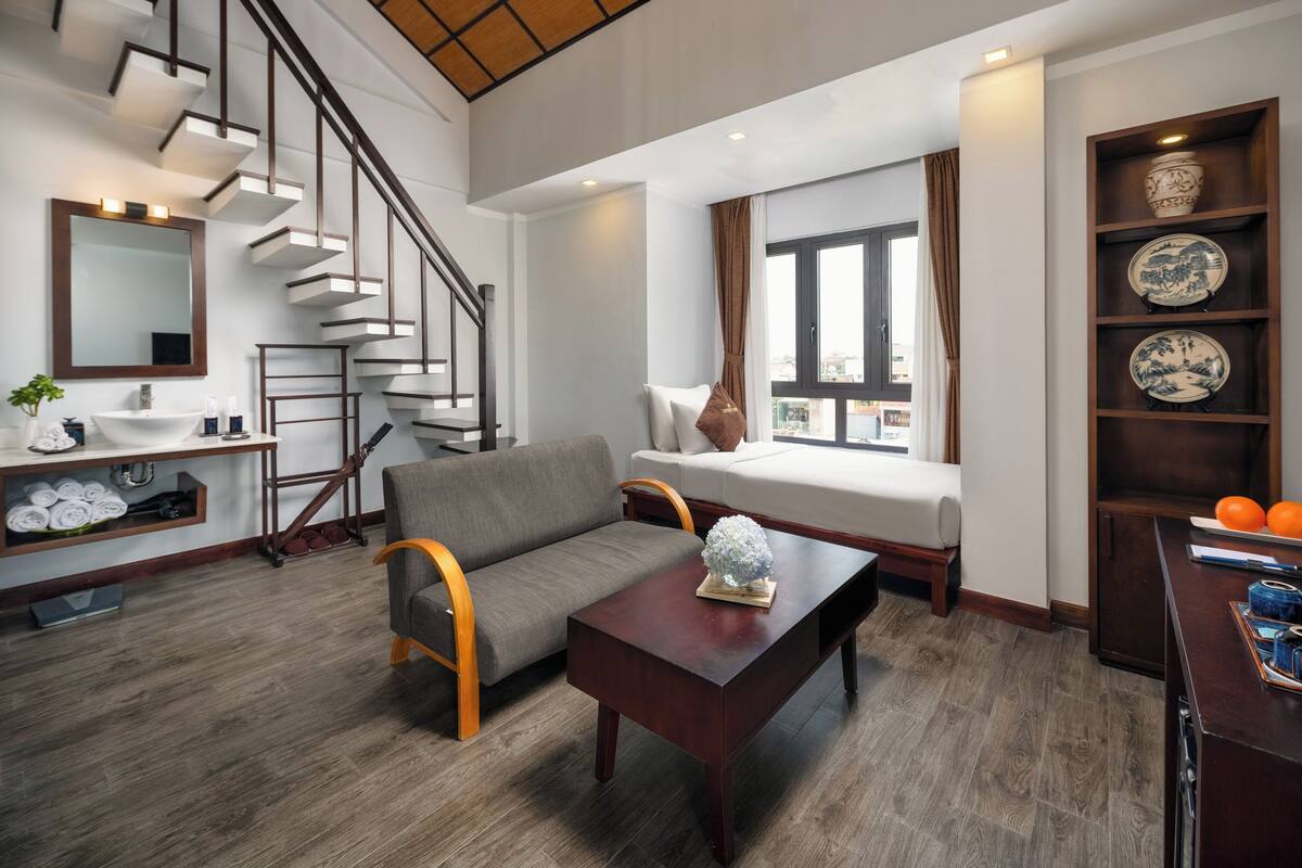 Uma sala de estar moderna com um sofá, mesa de centro e escada com acabamento em madeira.