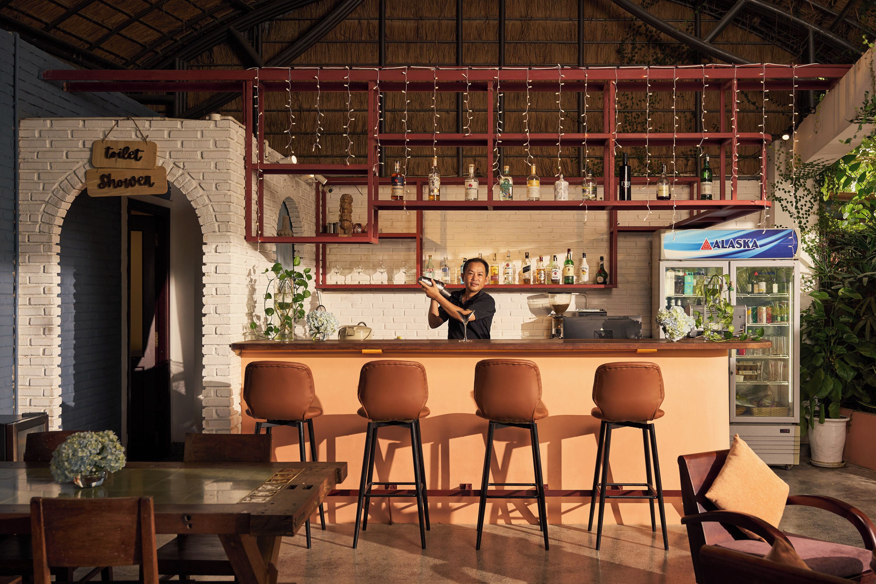 A bar area with a counter, stools, and a refrigerator stocked with beverages.