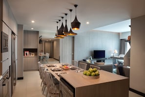 Una cocina moderna con una isla central, comedor y zona de estar con televisor.