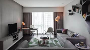 Una sala de estar moderna con un sofá, una mesa de centro, un televisor, un escritorio y una estantería.