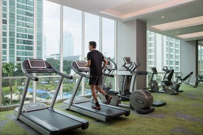 Un gimnasio con cintas de correr, bicicletas estáticas y una máquina de remo.