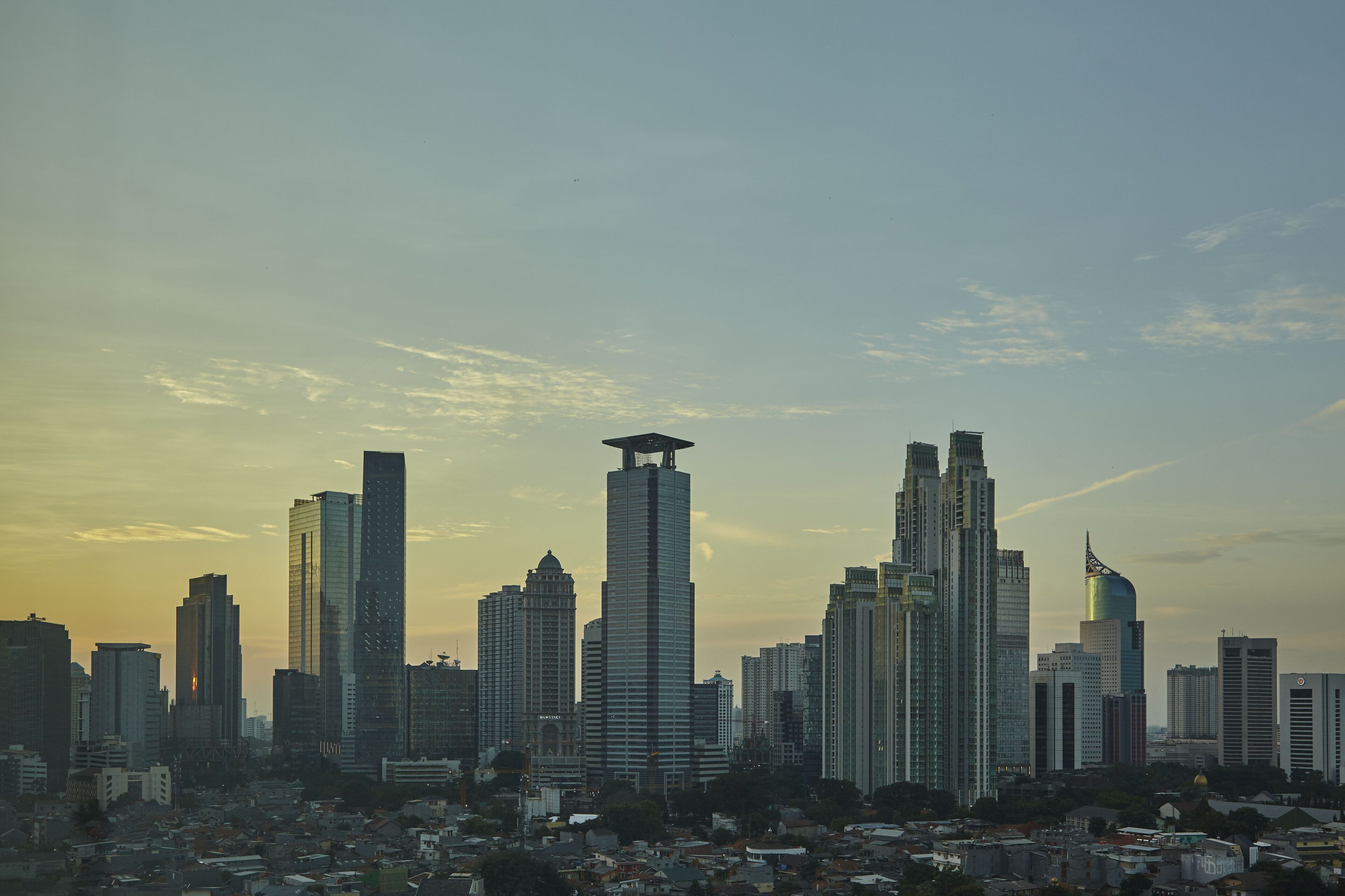A cityscape with multiple high-rise buildings, including a prominent skyscraper with a unique top structure.