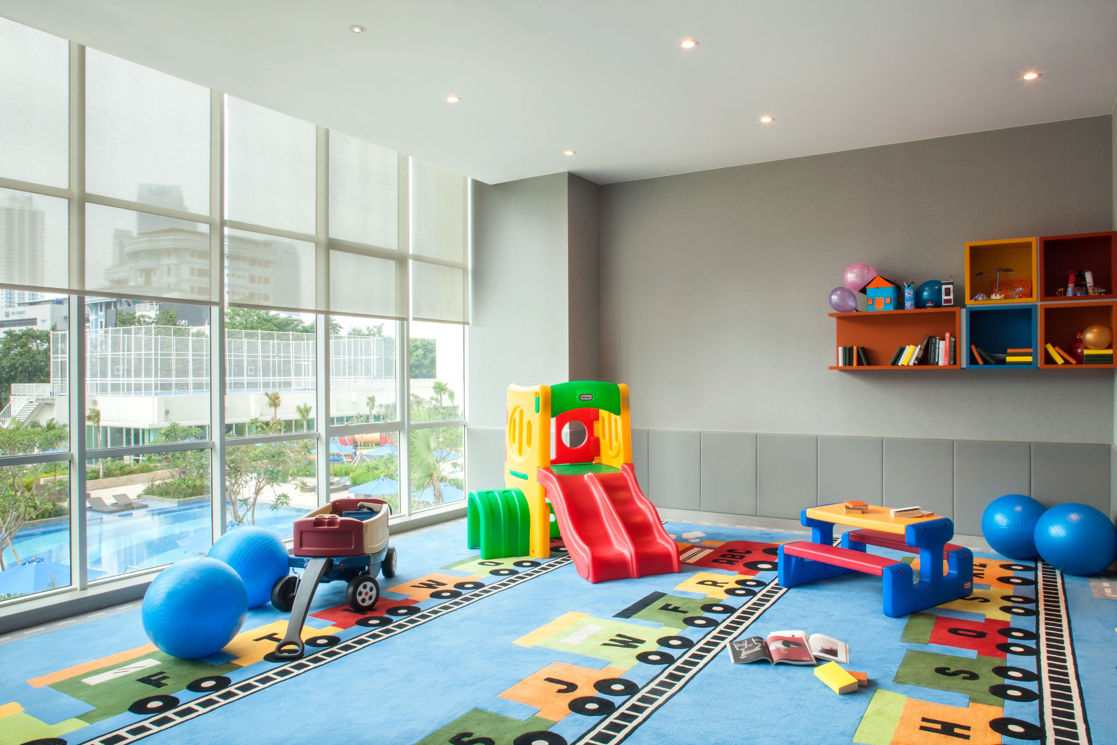 Un espace de jeux pour enfants avec un toboggan, des jouets colorés et une vue par la fenêtre.