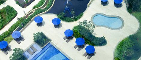 A pool area with lounge chairs and umbrellas, a children's play area, and a small pool.