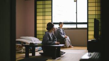 A traditional Japanese room with tatami flooring, a low table, and a television.