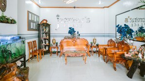 A spacious living room with a large wooden sofa, matching chairs, and a fish tank. - Jazmine's Place (Coron)