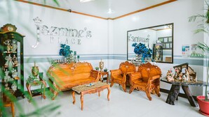 A room with a large mirror, a sofa set, a wooden cabinet, and a sign reading "Jazzmine's Place". - Jazmine's Place (Coron)