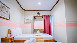 A hotel room with two beds, a wooden headboard, a nightstand, a framed picture, a small plant, and a window with curtains. - Jazmine's Place (Coron)