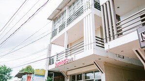 A multi-story building with a ground-level shop and a balcony with potted plants. - Jazmine's Place (Coron)