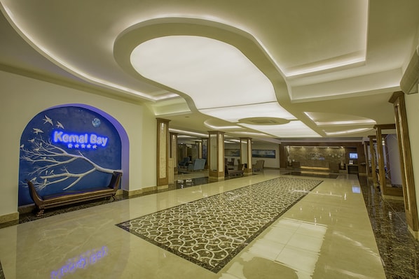 Welcome to our lobby, featuring a central reception desk with digital display and a comfortable bench.
