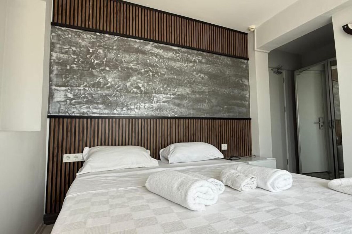 A hotel room with a large bed, a wooden headboard, a wall-mounted artwork, and a shower area.