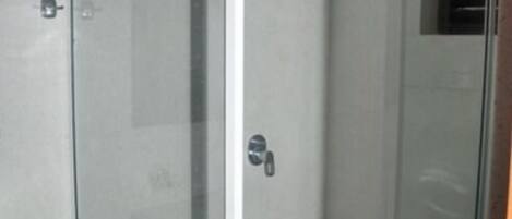 Box doccia in vetro con porta bianca e una piccola finestra.